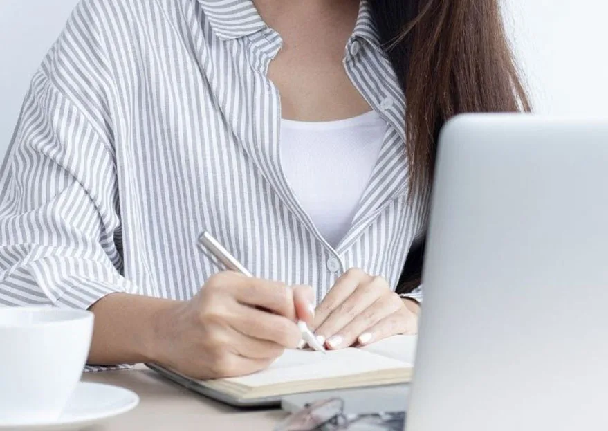 Kvinde der tager noter foran computer